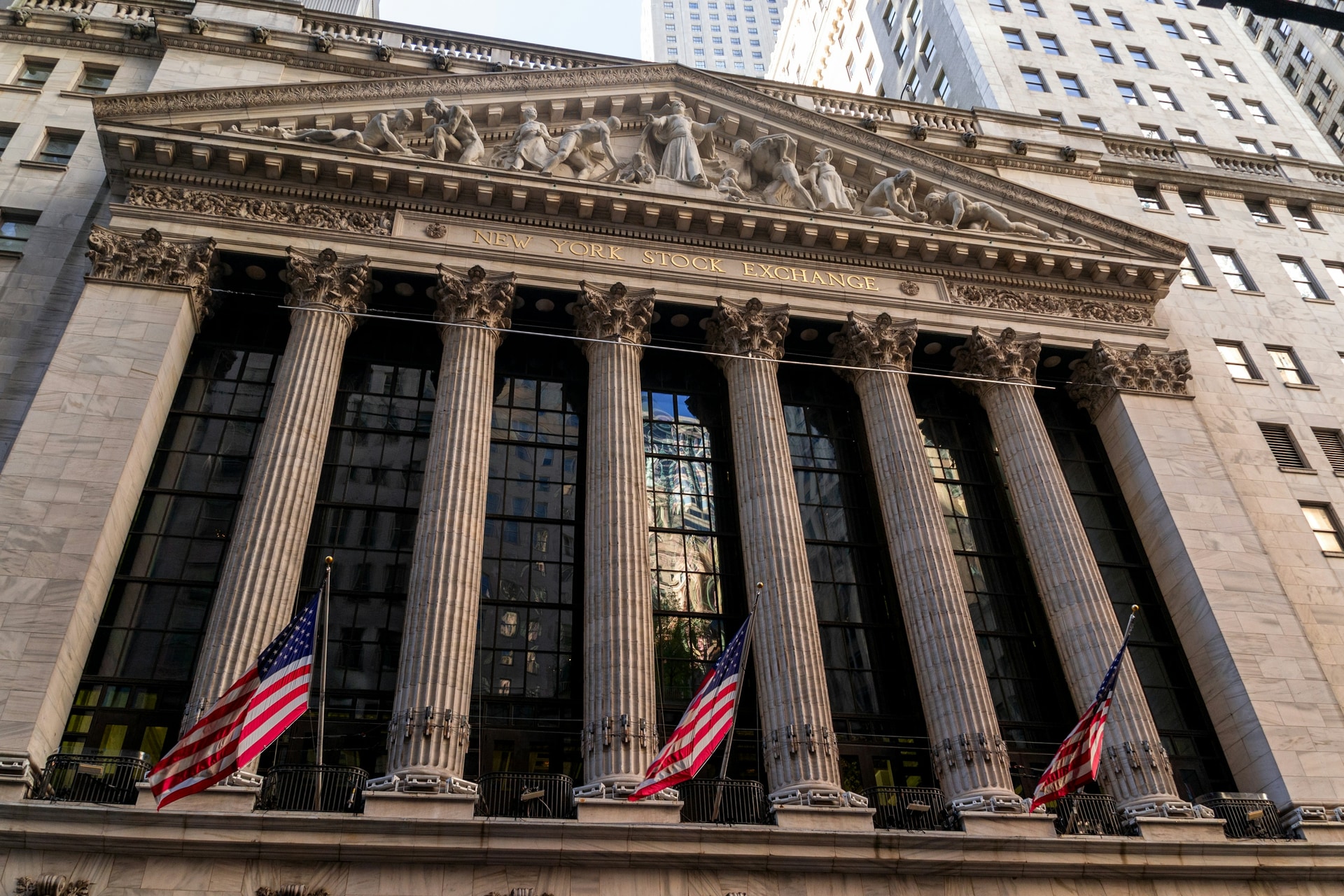 New York Stock Exchange facade with American flags on Wall Street